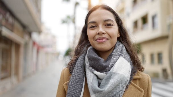 Jonge mooie Spaanse vrouw glimlachend vol vertrouwen op straat - Foto, afbeelding