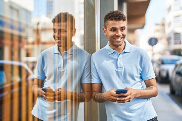 アフリカ系アメリカ人の男が路上でスマートフォンを使って笑顔で - 写真・画像