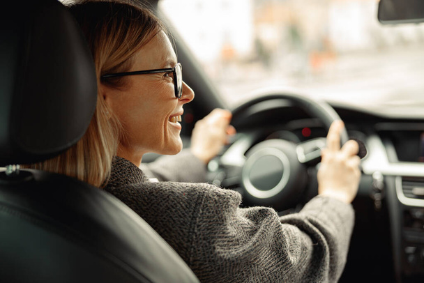 Donna guida auto e tenendo entrambe le mani sul volante sulla strada per il lavoro. Foto di alta qualità - Foto, immagini