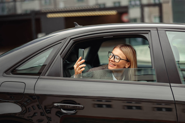 Mujer de negocios tomando fotos de atracciones desde el asiento trasero del coche en el camino al trabajo. Foto de alta calidad - Foto, imagen