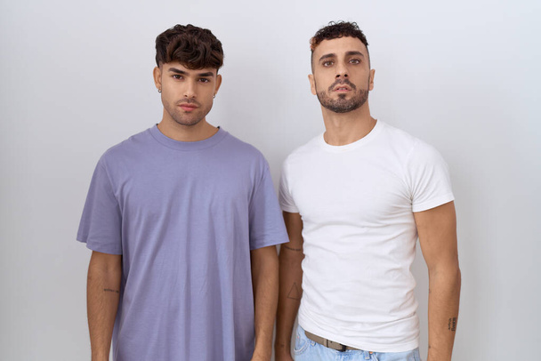 Homosexual gay couple standing over white background relaxed with serious expression on face. simple and natural looking at the camera.  - Fotografie, Obrázek