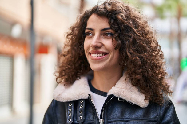 Junge hispanische Frau lächelt selbstbewusst und schaut auf der Straße zur Seite - Foto, Bild