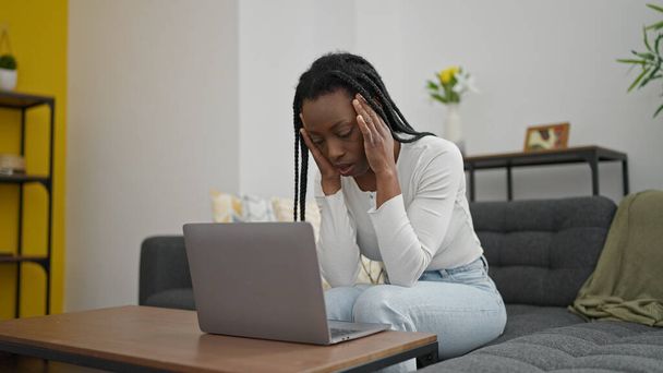 Evde dizüstü bilgisayar kullanan Afrikalı Amerikalı bir kadın. - Fotoğraf, Görsel