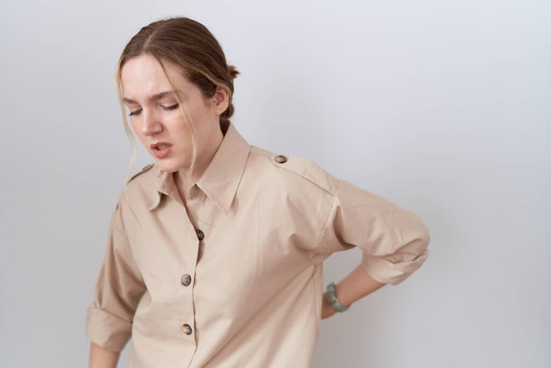 Young caucasian woman wearing casual shirt suffering of backache, touching back with hand, muscular pain  - 写真・画像
