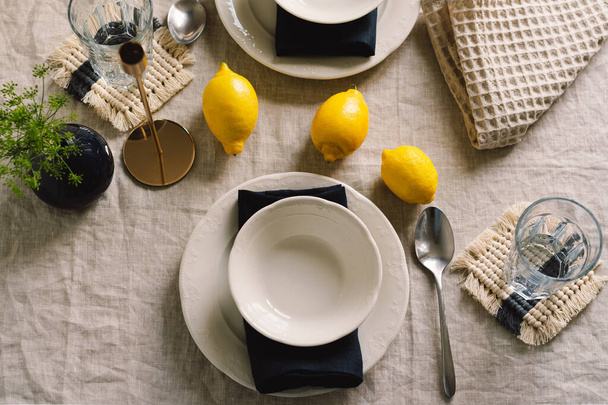 Mesa vintage con servilletas de lino y limones amarillos. Mesa decorativa. De cerca. Acogedora comida tranquila en la mañana bajo el sol. - Foto, imagen