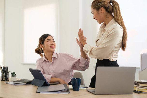 Two young female employees giving high five celebrating success in office. - Fotoğraf, Görsel