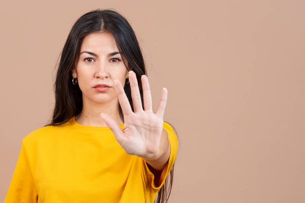 Mulher caucasiana gesticulando proibição com a mão em estúdio com fundo marrom - Foto, Imagem
