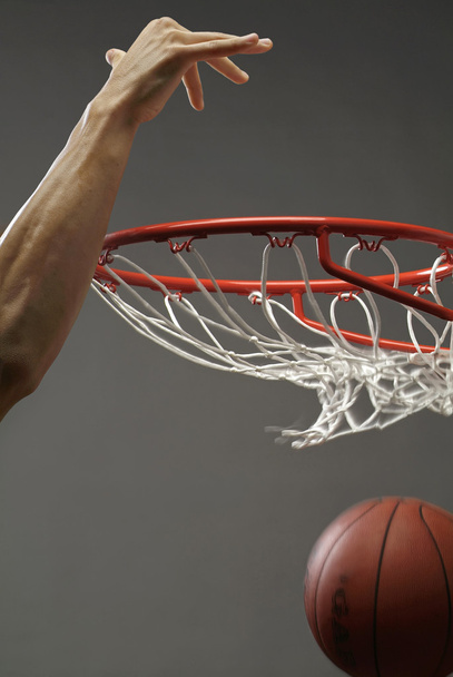 egy ember dunking át a Hálón, egyik kezével kosárlabda - Fotó, kép