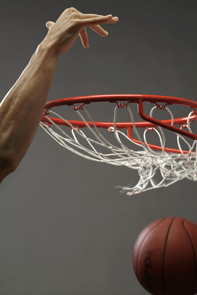 Un hombre metiendo una pelota de baloncesto a través de una red con una mano
 - Foto, imagen