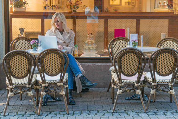 mulher jovem empresária senta-se em um café atrás de um laptop. Negócios, trabalhar online. Foto de alta qualidade - Foto, Imagem