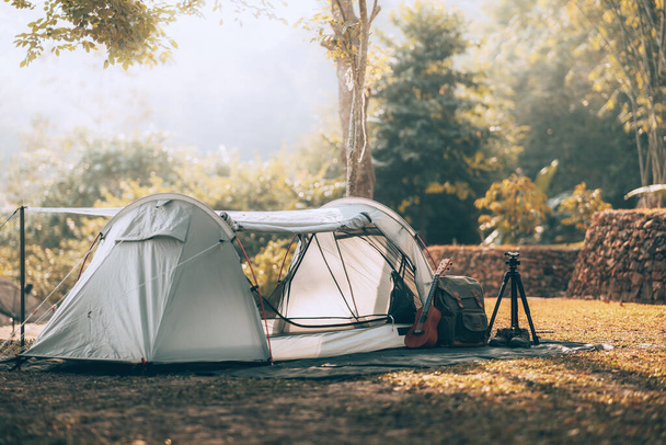 Gray tent on the grass in the forest The view behind is the mountain in the morning. Camping, Travel and holiday concept. - Foto, Imagem
