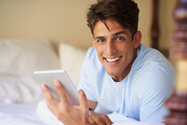 ¿Sabes qué puedes hacer con esta cosita? un joven guapo usando su tableta digital en casa - Foto, imagen