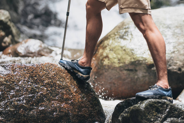 Hikers use trekking pole with backpacks walking through the rock and water on stream in the forest. hiking and adventure concept. - 写真・画像