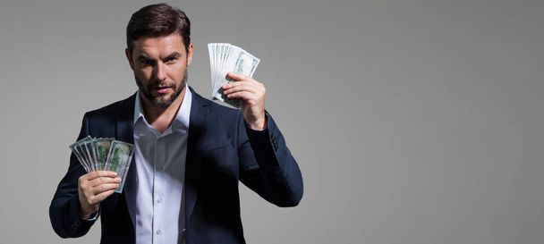 Portrait business man holding cash dollar bills over gray background. Big luck, banner. Dollar cash money concept. Rejoices to win cash. Man hold cash money. Financial luck and success - Foto, afbeelding