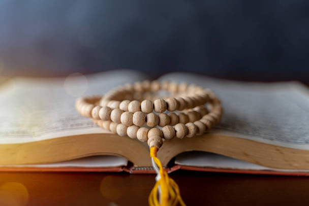 Quran with written arabic calligraphy meaning of Al Quran. Ramadan Mubarak. Ramadan kareem. Holy Islamic Book Koran with rosary beads on wooden background.  - Foto, Bild