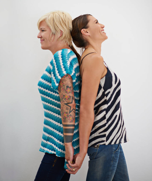 De espalda a espalda y de la mano. una pareja lesbiana de pie de espaldas cogidas de la mano - Foto, imagen