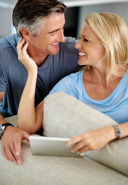 Não há lugar onde preferisse estar. um casal maduro afetuoso usando um tablet digital enquanto sentado em seu sofá em casa - Foto, Imagem