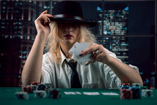 Nainen jälleenmyyjä hattu pelikortteja ja pelimerkkejä kasino katsomassa peliä. Naispuolinen pokeridiileri. kasino - Valokuva, kuva