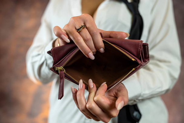 Close-up image of girl's hands with an open empty purse in her hands. An empty wallet is a woman without money in her wallet. Wallet made of natural blue leather - Fotó, kép