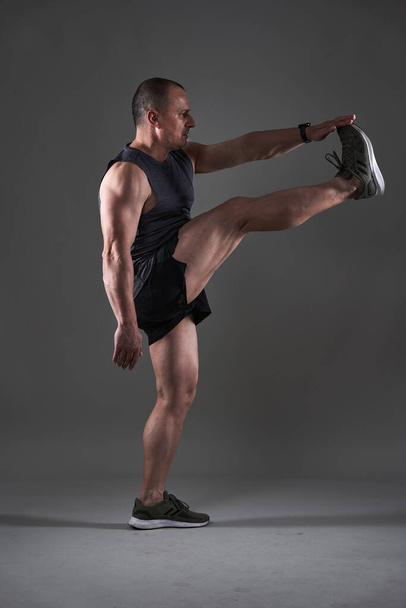 Full body shot of a mature man doing a fitness workout on gray background - Фото, зображення