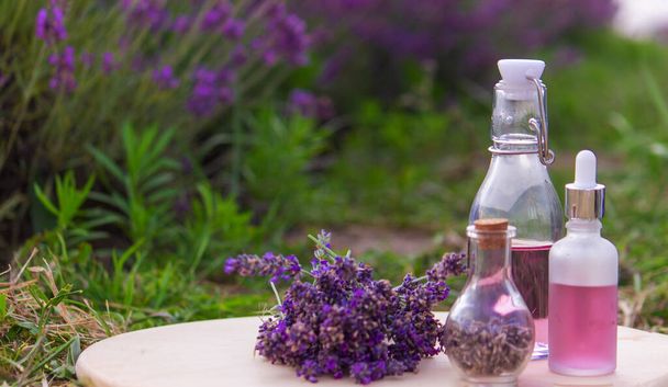 jars with lavender oil, lavender flowers, on the background of a lavender field. Selective focus - Photo, Image