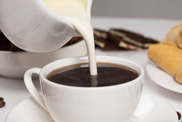 Крем з молочного глечика вливають у каву, роблячи каву з вершками, капучино
 - Фото, зображення