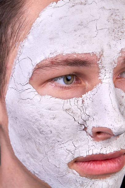 Close up young man with white cosmetic facial mask. Dried mask with cracks. - Fotografie, Obrázek