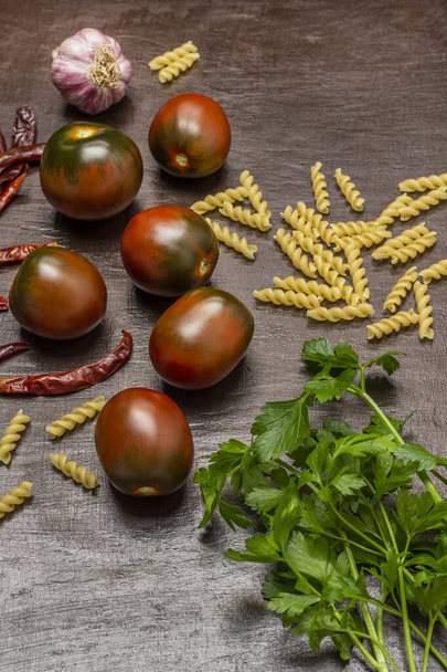Parsley sprigs, tomatoes and pasta. Top view. Brown background. - Φωτογραφία, εικόνα