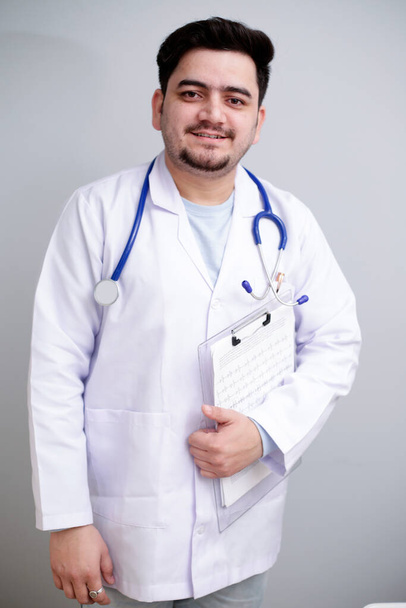 A young doctor is standing and holding notepad in hand. - Foto, afbeelding