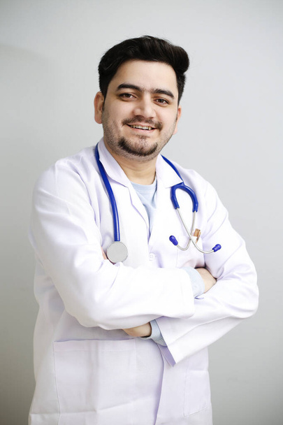 A young doctor is standing with crossed arms and smiling. - Photo, image