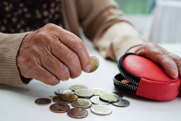 Retired elderly woman counting coins money and worry about monthly expenses and treatment fee payment. - Foto, Imagem