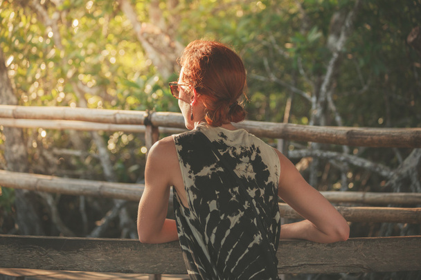 Woman sitting on bench in jungle - Zdjęcie, obraz