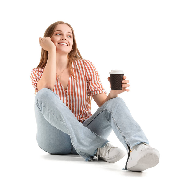 Hermosa chica con taza de café sentado sobre fondo blanco - Foto, Imagen