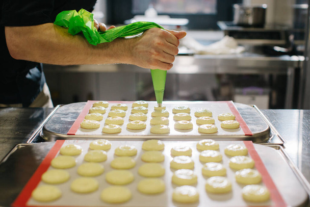A confectioner makes macaroons in a pastry shop. - Foto, imagen