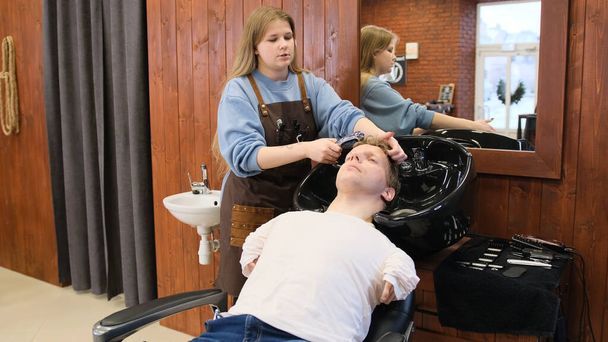 Ein Friseurmädchen wäscht einem Mann mit begrenzten Möglichkeiten in einem Schönheitssalon die Haare. - Foto, Bild