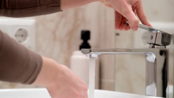 Beyaz tenli bir insan yazın ellerini suyla yıkar, cilt hijyeni ve koronavirüsten korur, parmaklarını yıkar, bakterilerin yayılmasını engeller, su sıçratır ve sinek düşer. - Video, Çekim