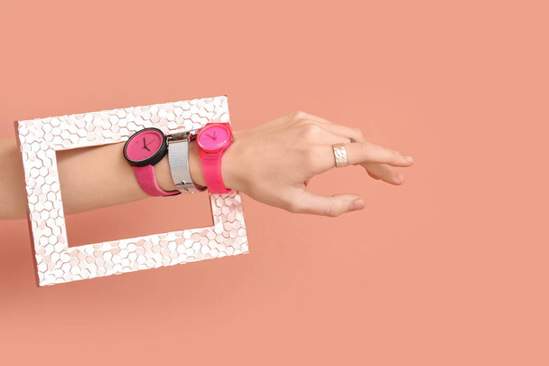Mujer con elegantes relojes de pulsera y marco sobre fondo rosa - Foto, Imagen