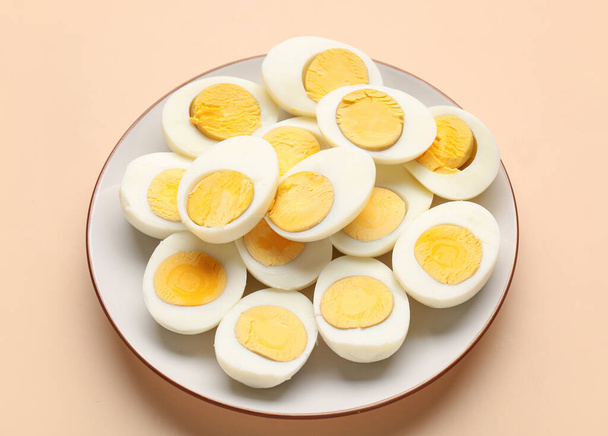 Plate with halves of delicious boiled eggs on beige background - Photo, Image