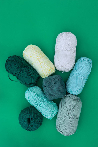 緑の背景に置かれたさまざまなボールや糸のスキンのトップビュー。異なる糸・繊維質の概念. - 写真・画像