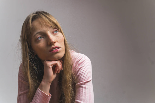 medium closeup shot of a light-haired girl thinking, isolated on grey background studio shot. High quality photo - Фото, изображение