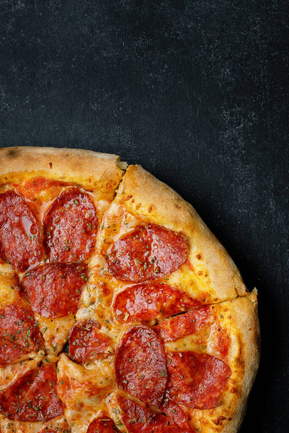 Pizza s klobásou, sýrem a kořením, na tmavém pozadí - Fotografie, Obrázek