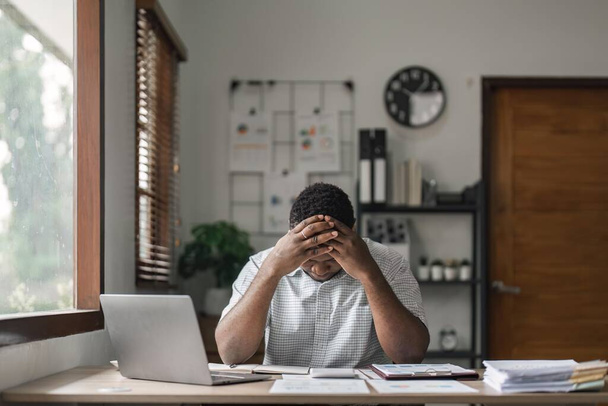 Tired depressed african businessman frustrated by business failure bankruptcy looking at laptop feel exhausted having headache, upset stressed black office worker worried about problem at work. - Photo, Image