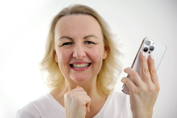 happy satisfied woman smiles strongly holds phone cheerful smile pleasant phone call positive emotions squinted eyes - Photo, Image