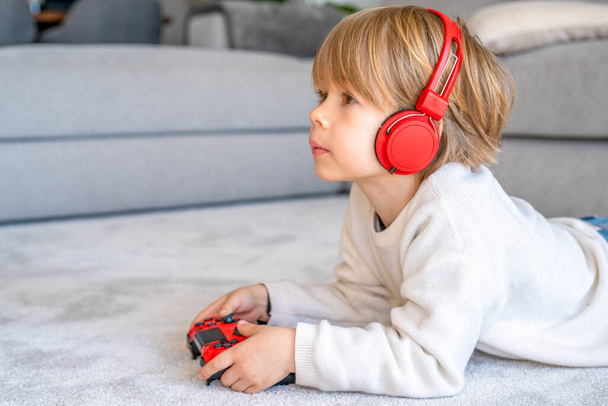 Little boy playing video game console using joystick or controller while sitting at home real people family leisure concept - 写真・画像