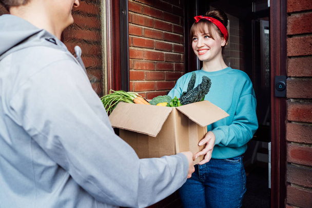 Home fresh food delivery. Woman taking cardboard box with vegetables and fruits. Support local farmer food production. New Start of a healthy life, weight loss concept. Online food order. Recipe box. - Fotó, kép
