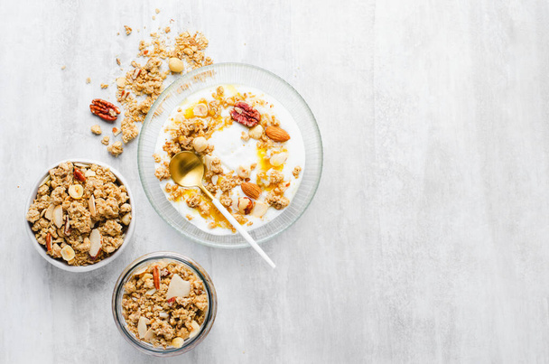 Granola met nootje Mix en yoghurt in een schaal, gezond ontbijt, muesli met gedroogde bessen op heldere achtergrond - Foto, afbeelding