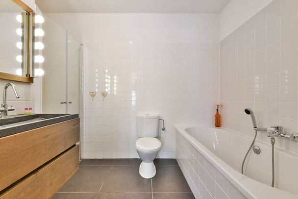 Tuvaleti, lavabosu ve küveti olan bir banyo küvetin yanındaki duvarda görünen renkle aynı. - Fotoğraf, Görsel
