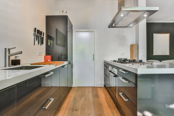 nowoczesna kuchnia z podłogi drewnianej i urządzeń ze stali nierdzewnej wiszące na ścianie w pokoju jest bardzo czyste - Zdjęcie, obraz