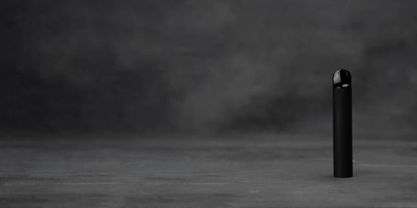 Black electronic cigarette vape on dark background with smoke. High quality photo - Foto, Imagen