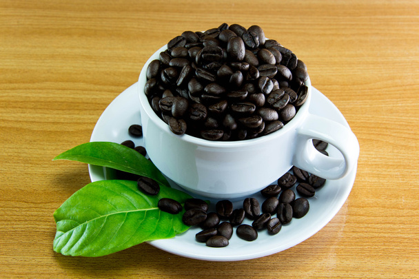 Natura morta tazza di chicchi di caffè e lascia il caffè sul tavolo di legno
 - Foto, immagini